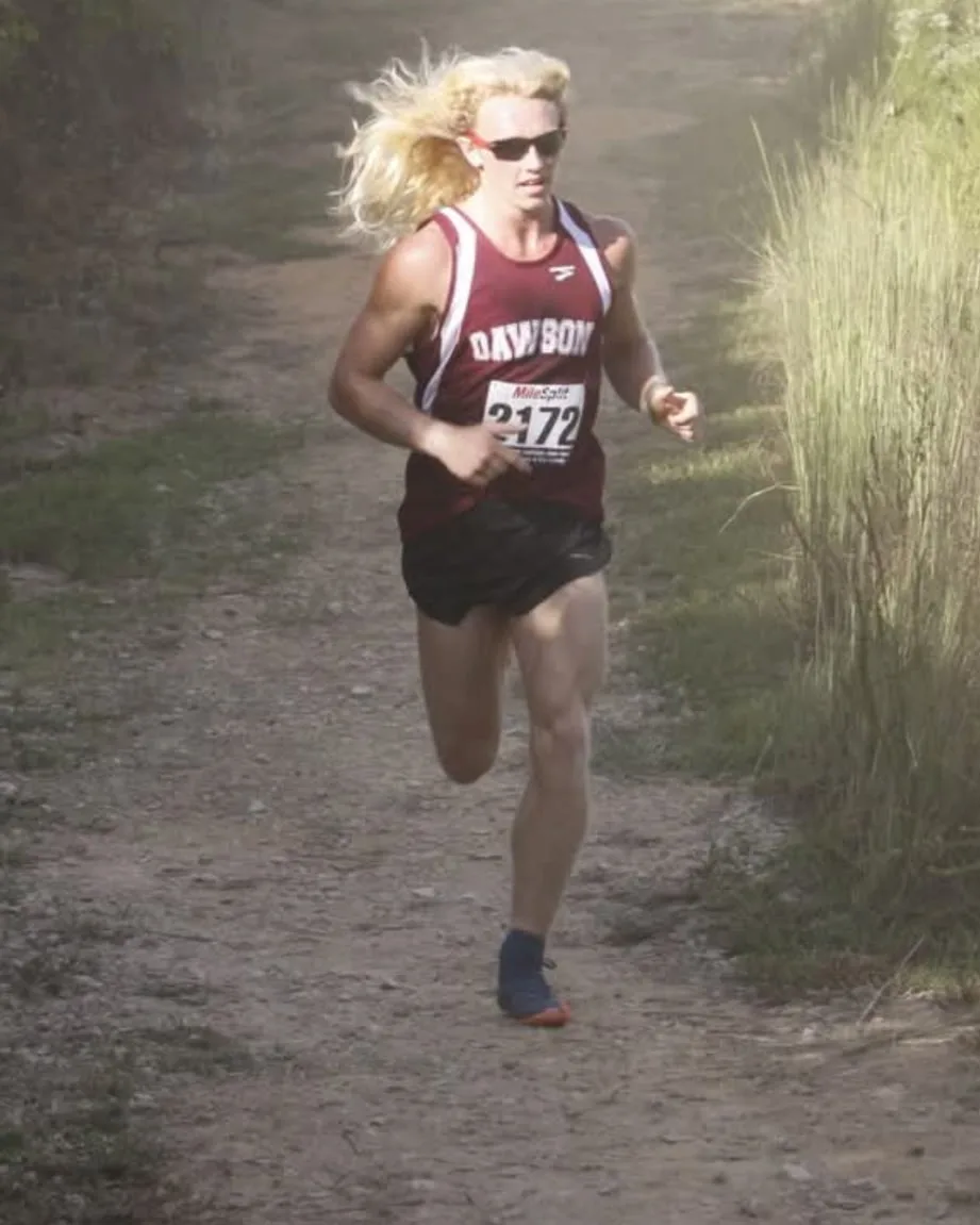 A young Cody Wood racing cross-country on a dusty trail, hair flying